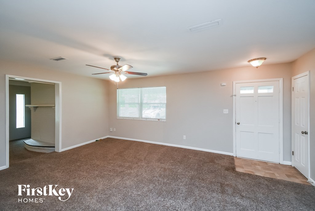 an empty living room with a ceiling fan and a closet