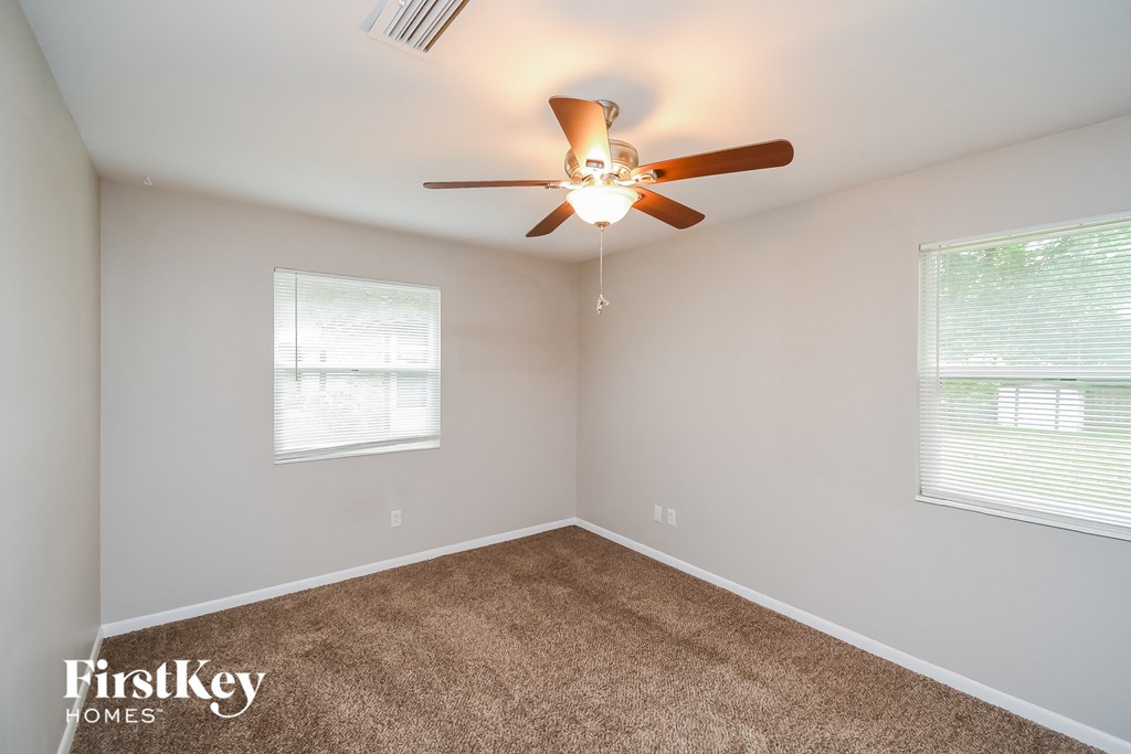 a bedroom with carpet and a ceiling fan and two windows