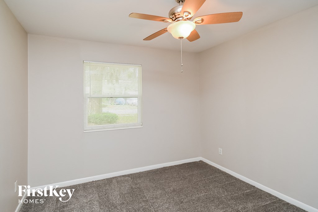 an empty room with a ceiling fan and a window