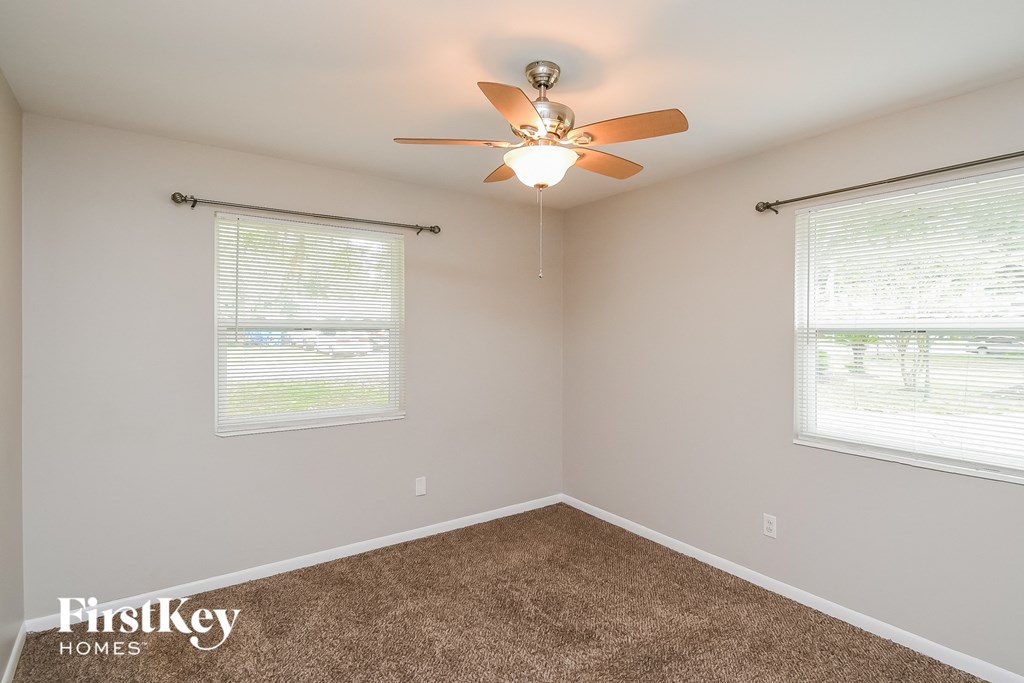 a bedroom with a ceiling fan and two windows
