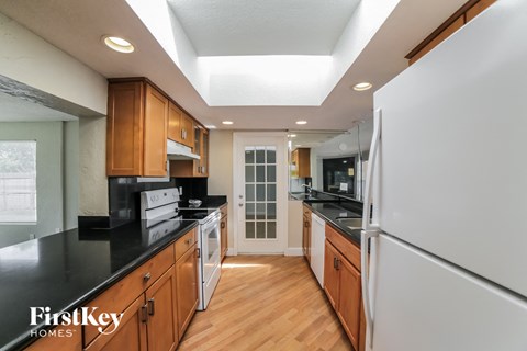 a kitchen with black counter tops and wooden cabinets and white appliances