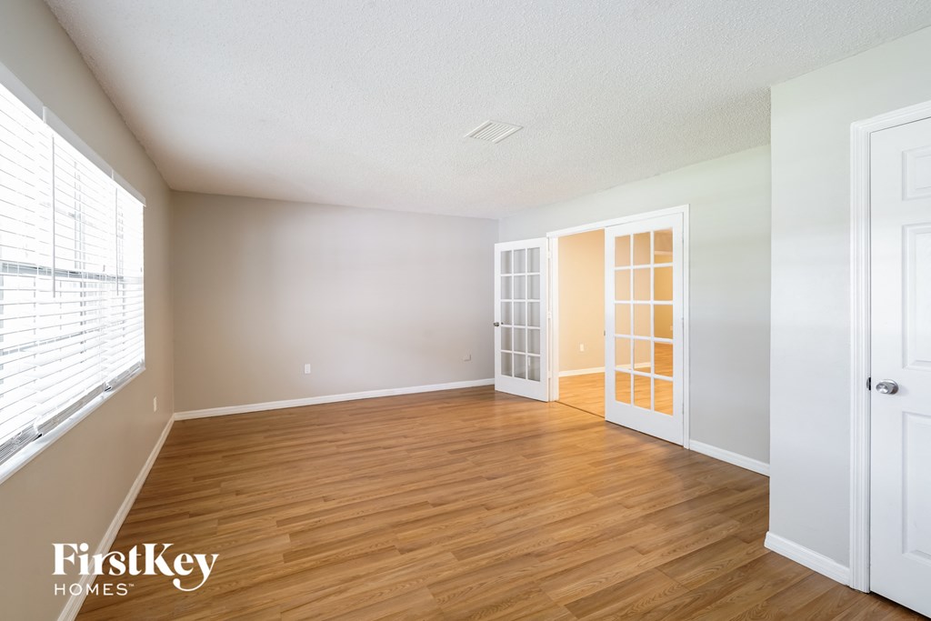 A room with wooden floors and white walls, with a door on the right.