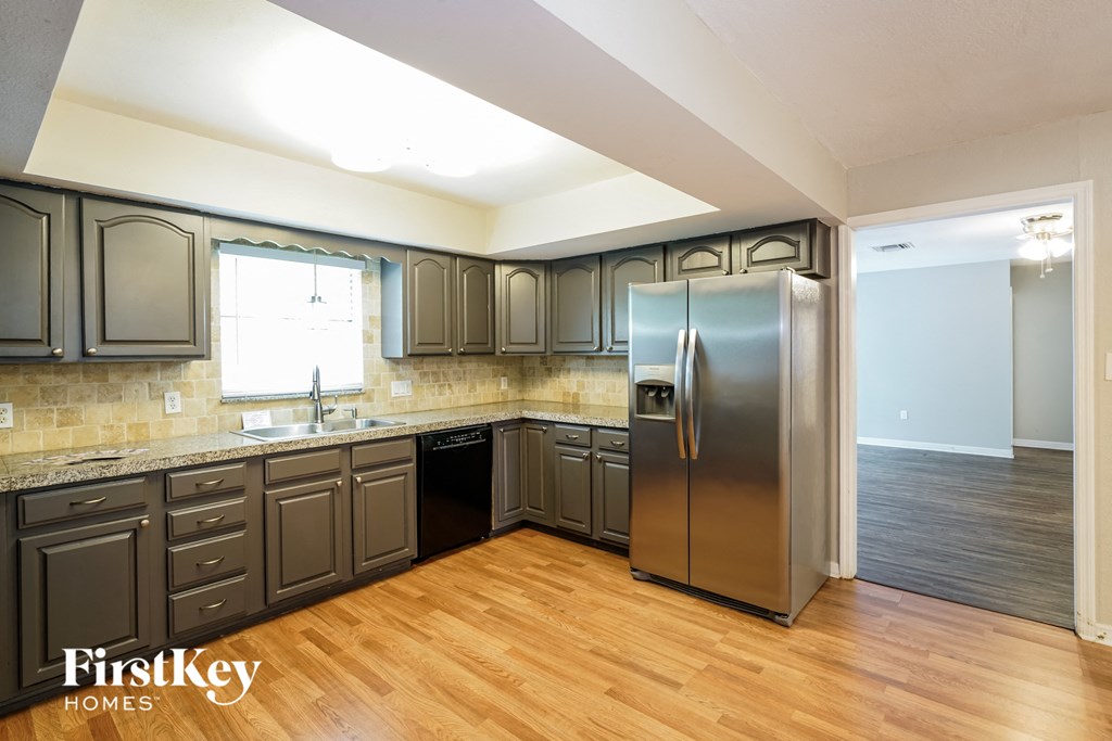 A kitchen with wooden floors and a stainless steel refrigerator.