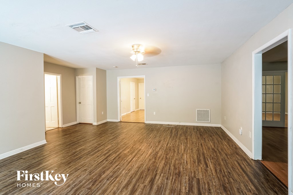 A spacious room with wooden flooring and a ceiling fan.
