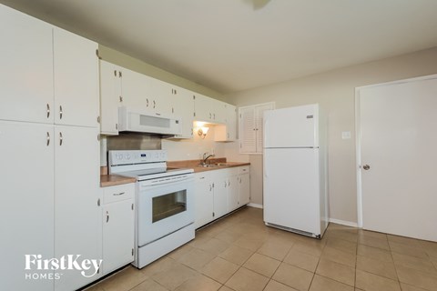 A kitchen with white cabinets and appliances.