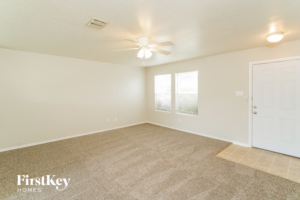 a spacious living room with carpet and a ceiling fan