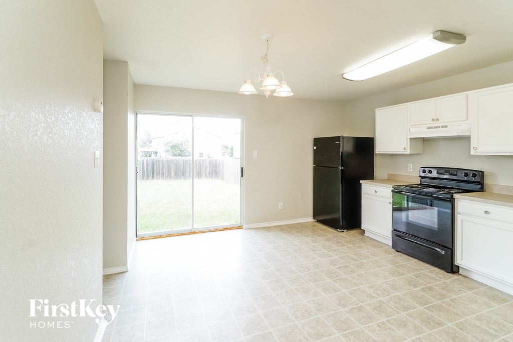an empty kitchen with black appliances and white cabinets
