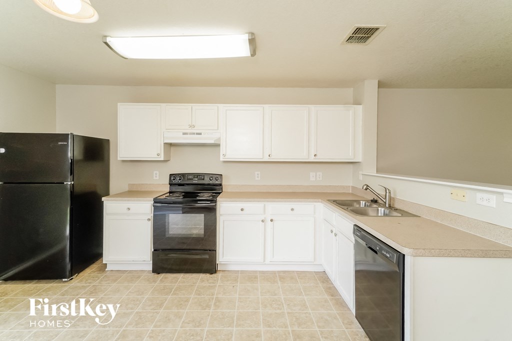 a kitchen with white cabinets and black appliances and a sink