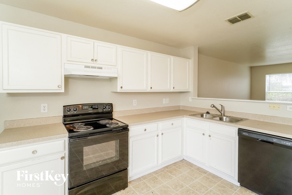 a kitchen with white cabinets and a stove and a sink