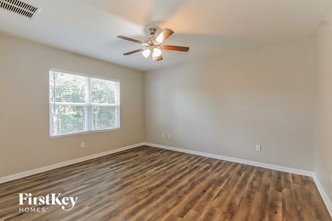 the spacious living room with hardwood floors and a ceiling fan