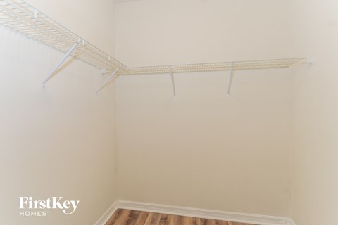 the closet of a bedroom with white walls and a white rack on the wall