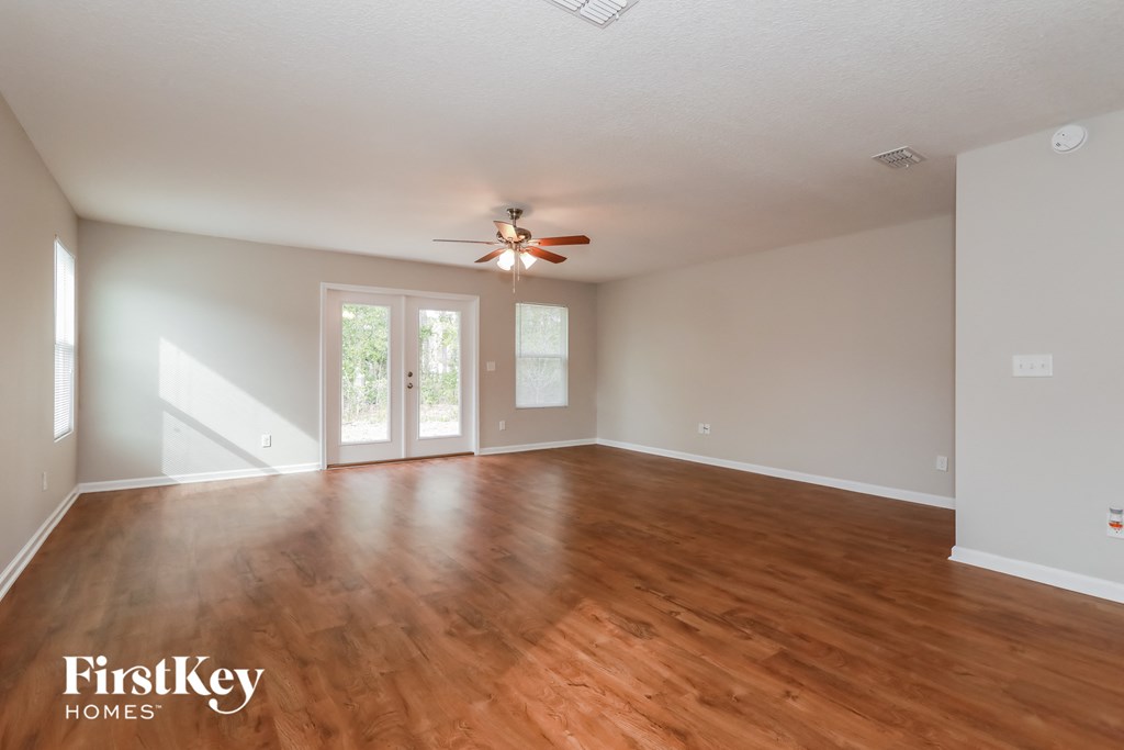 an empty living room with wood floors and a ceiling fan