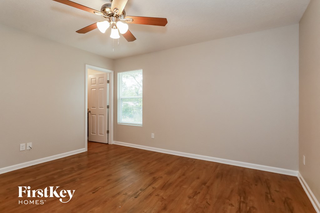 the living room of an empty house with wooden floors and a ceiling fan