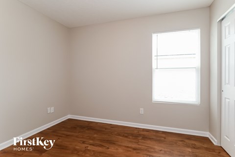 a bedroom with a wood floor and a window