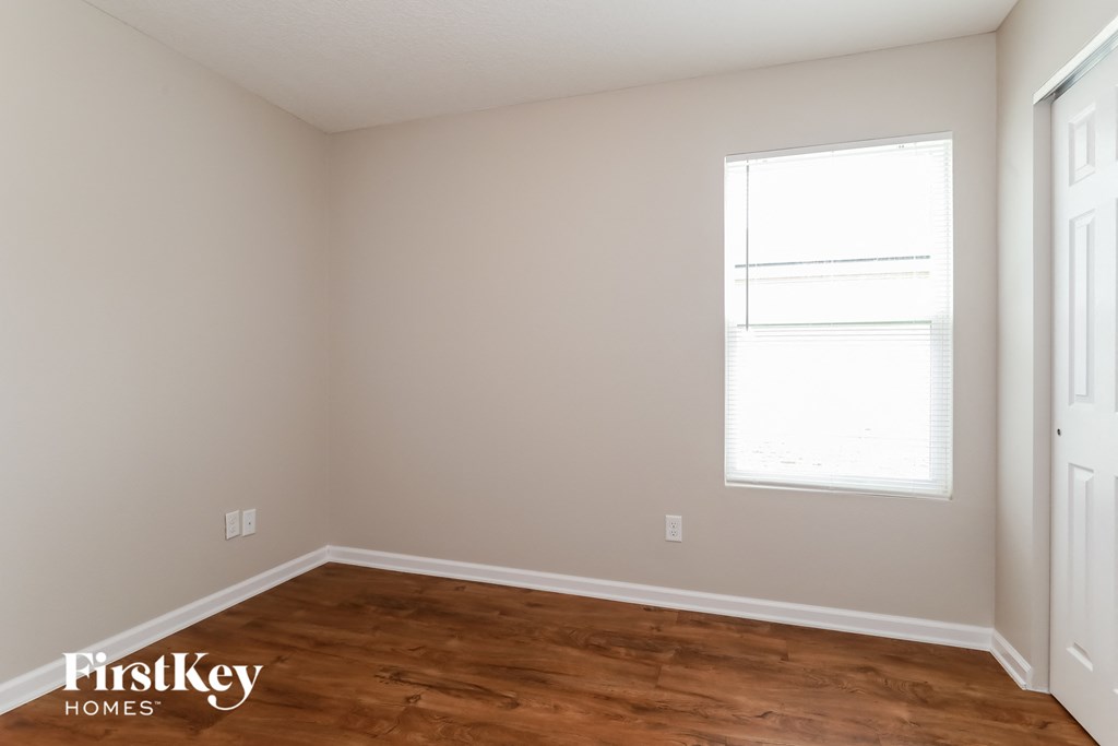 a bedroom with a wood floor and a window