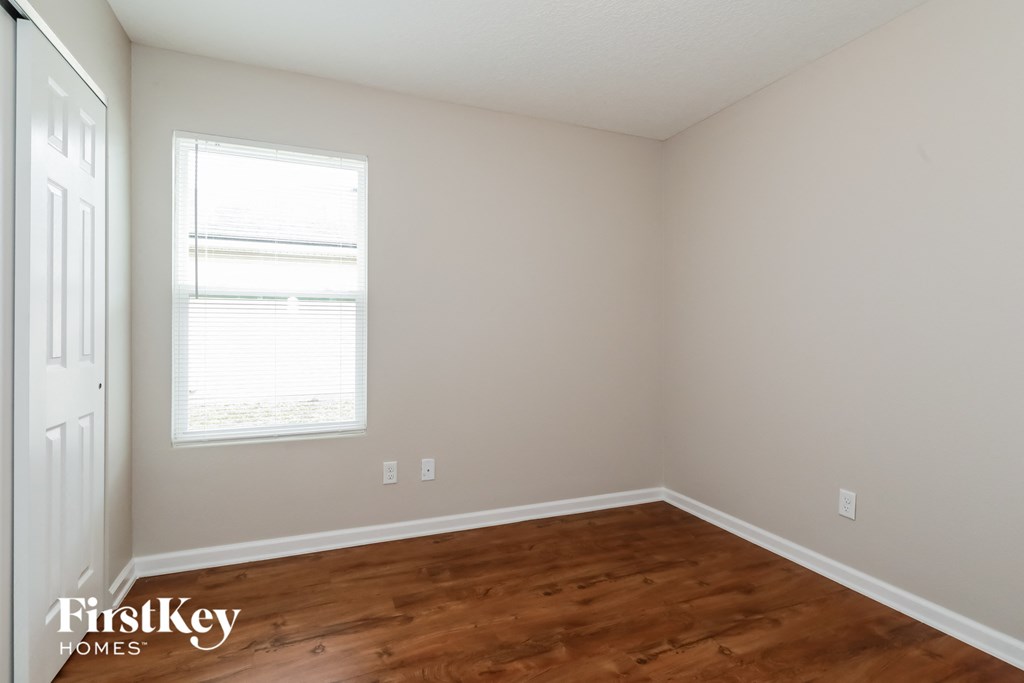 a bedroom with wood floors and a window