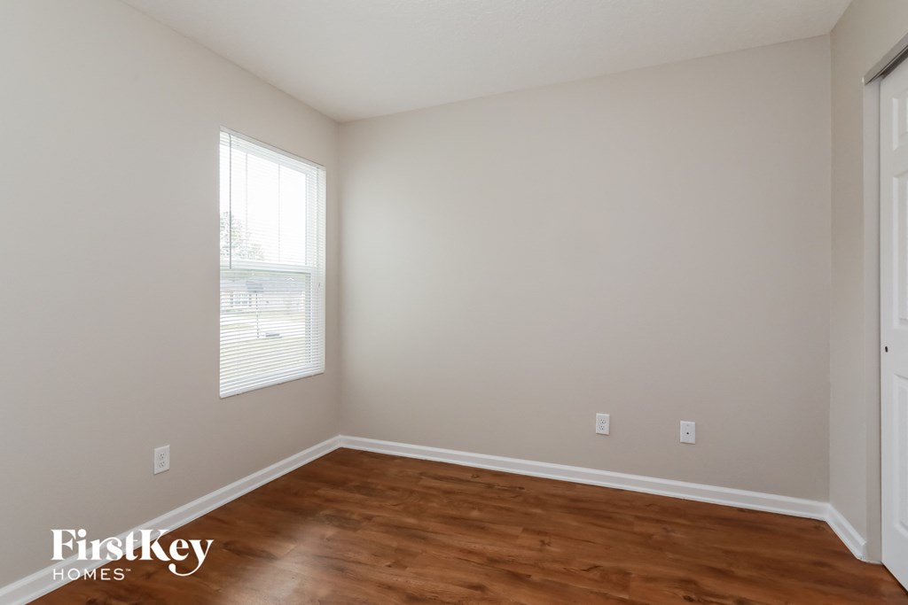 a bedroom with wood floors and white walls and a window