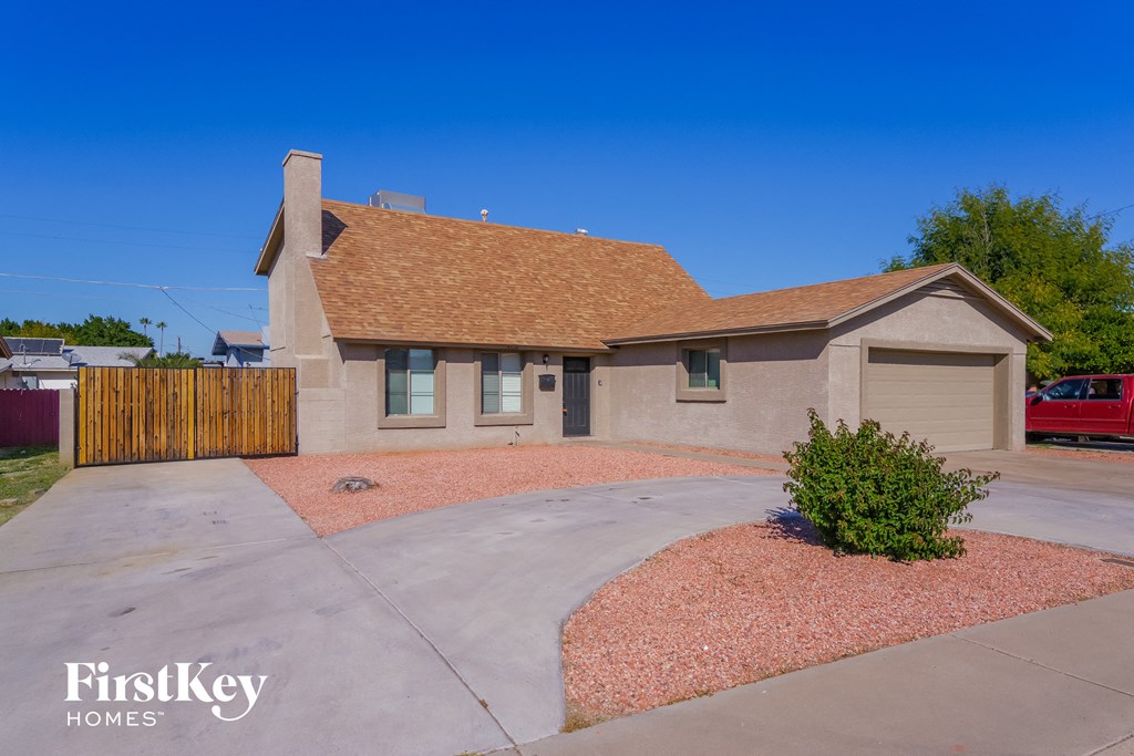 a home with a driveway and a house with a brown roof