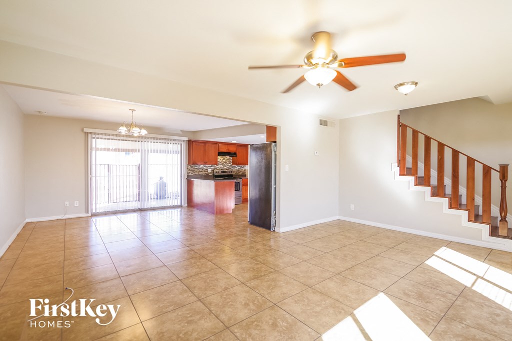 an empty living room with a ceiling fan and a staircase