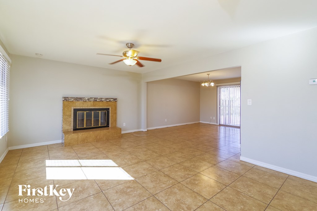 an empty living room with a fireplace and a ceiling fan