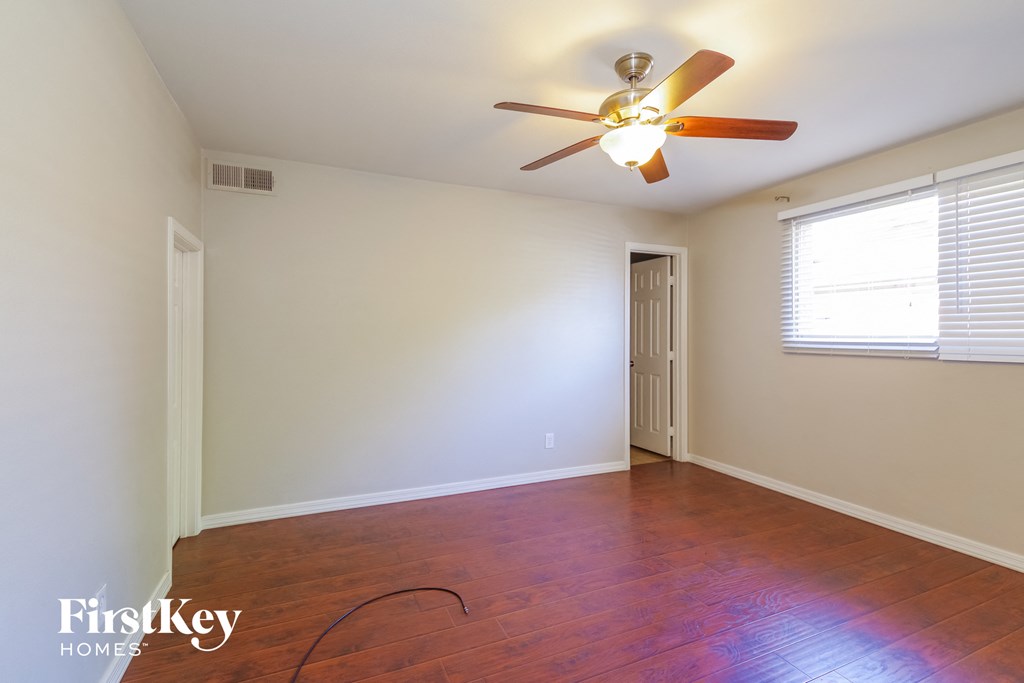 a empty living room with a ceiling fan and wood floors