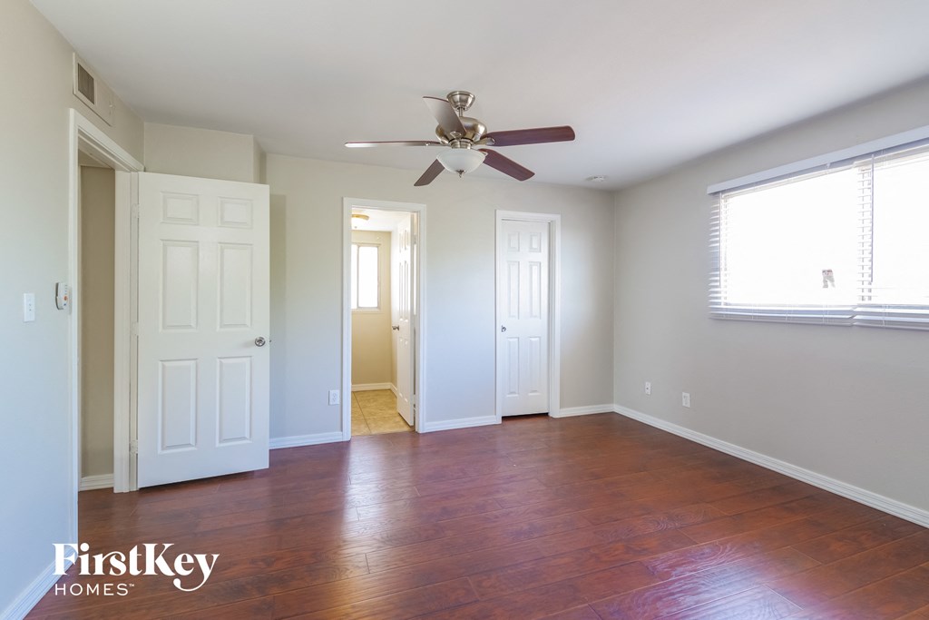 an empty living room with a ceiling fan and wood floors