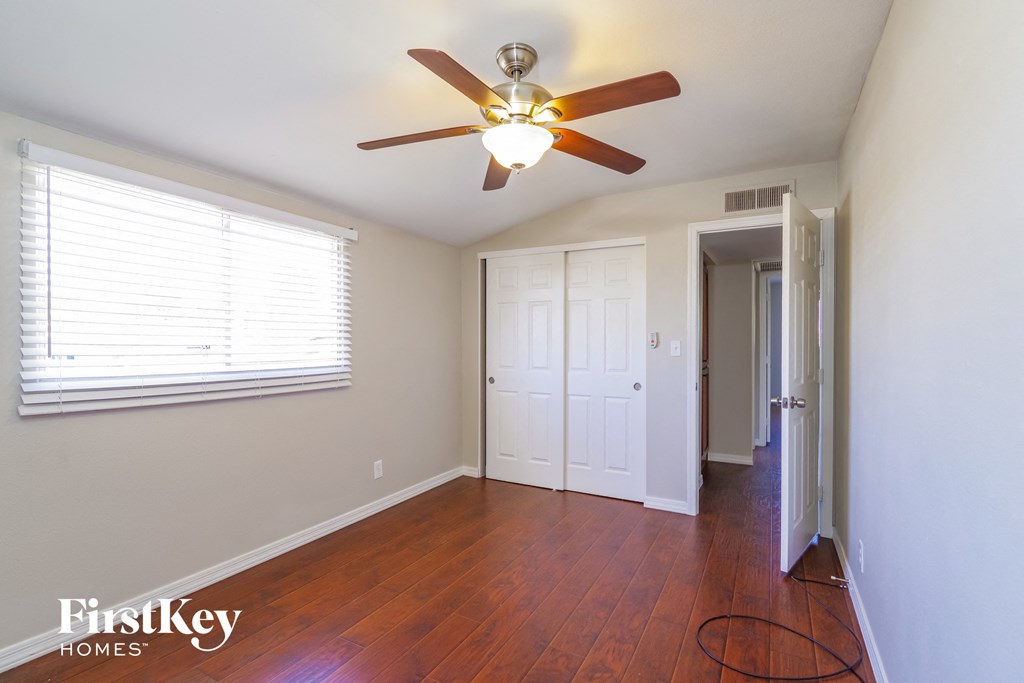a bedroom with a ceiling fan and a door to a closet