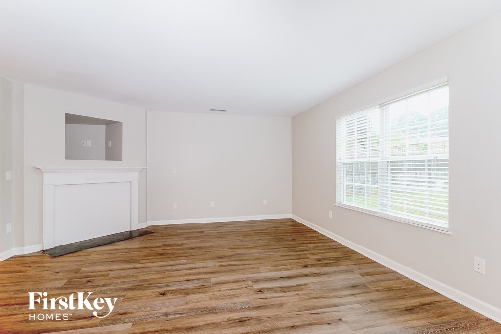 the living room with wood floors and white walls and a large window