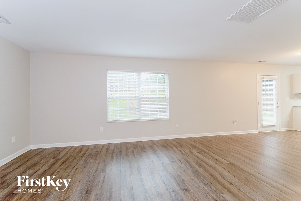 the living room of a home with wood floors and white walls