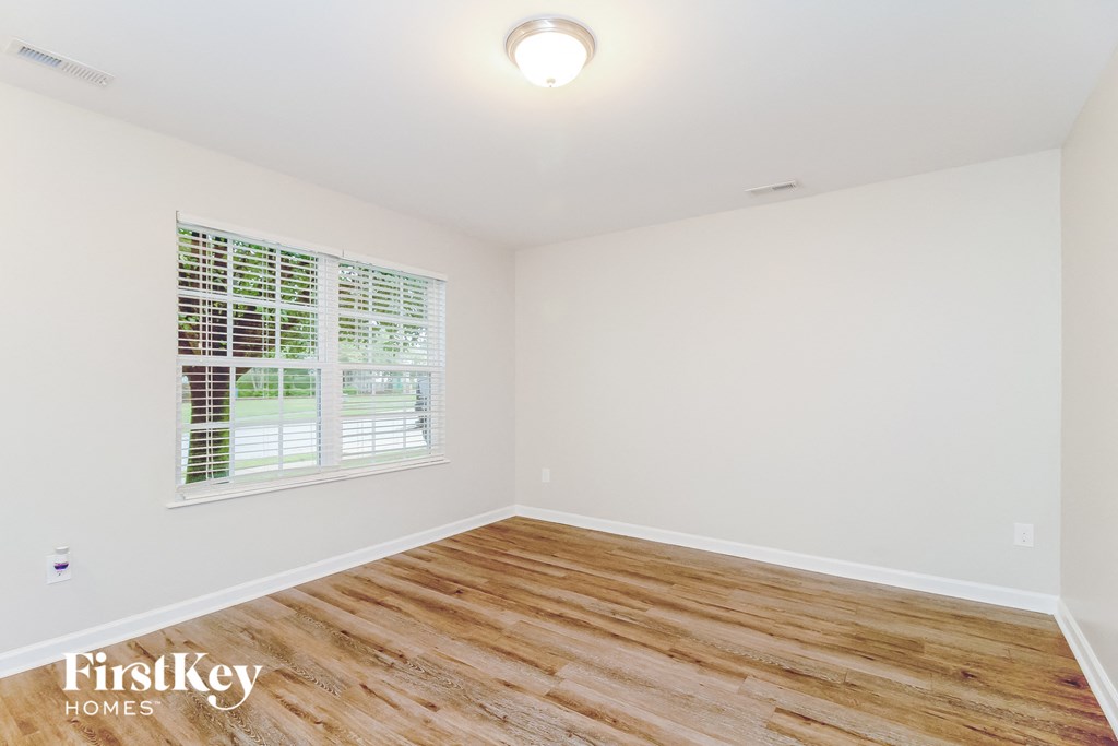 the living room of a home with wood flooring and a window