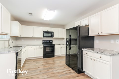 a white kitchen with black appliances and white cabinets