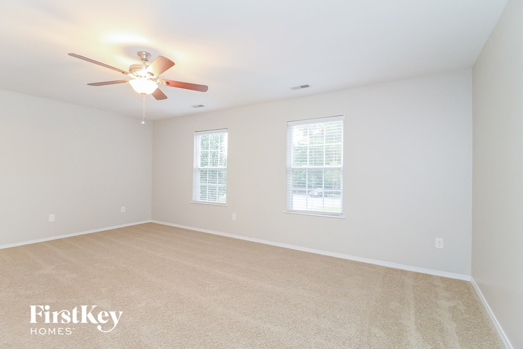 a spacious living room with white walls and a ceiling fan