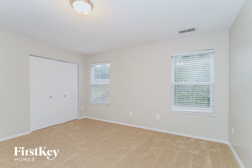 a bedroom with a carpeted floor and a white door and window