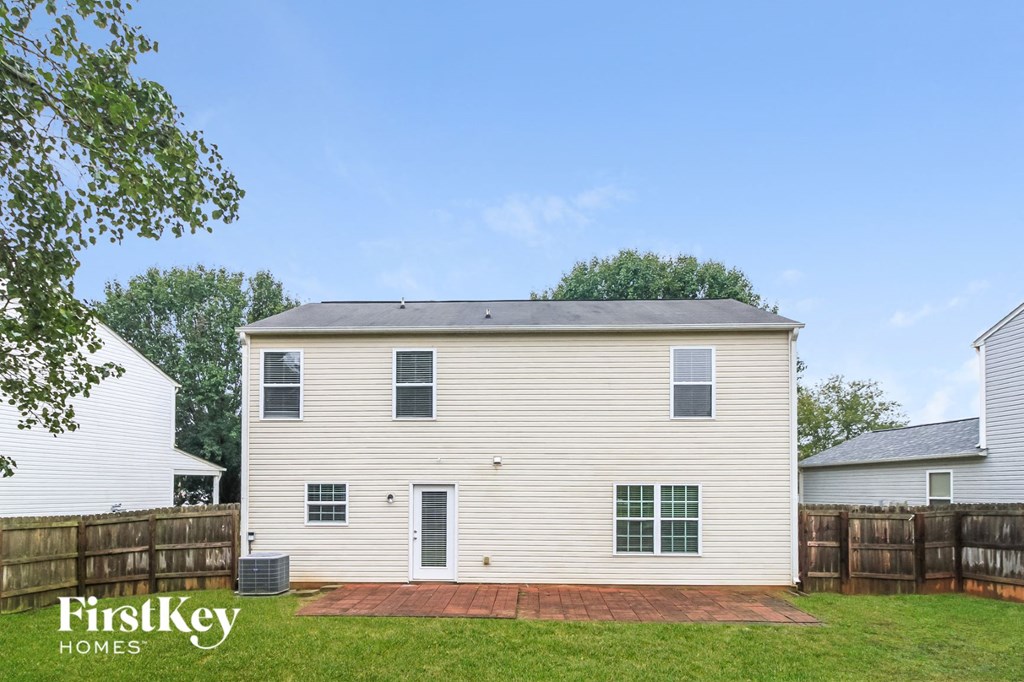 side view of a white house with a yard and a wooden fence