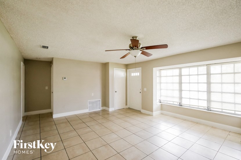 an empty living room with a ceiling fan and tiled floors