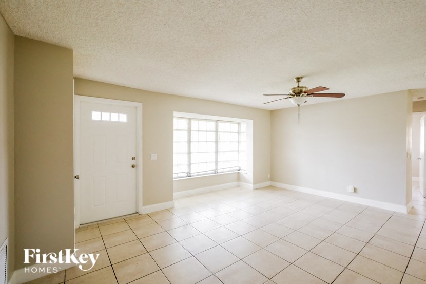 an empty living room with a ceiling fan and tiled floors