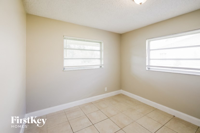 an empty room with a tiled floor and two windows
