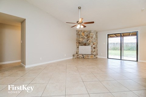 A spacious room with a fan and a stone fireplace.