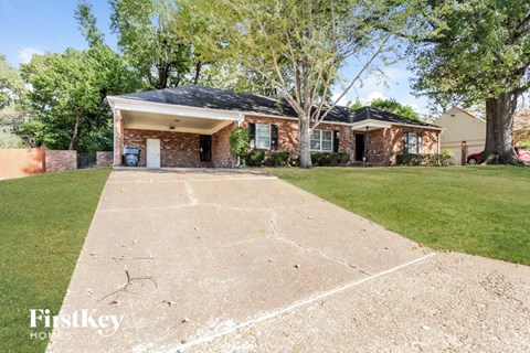 a brick house with a driveway and a lawn