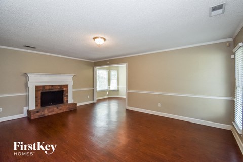 A spacious room with a fireplace and wooden floors.