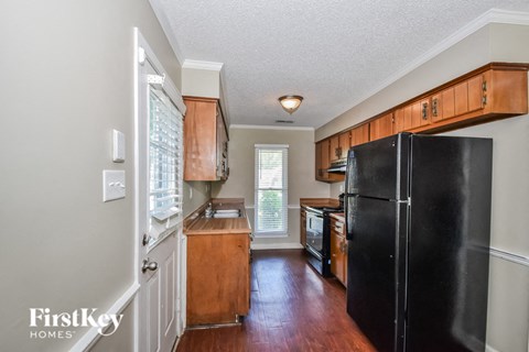 A kitchen with wooden cabinets and a black refrigerator.