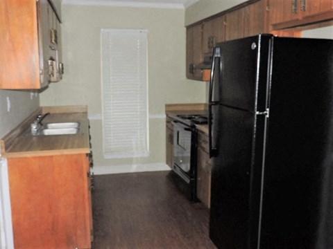 A black refrigerator is in the corner of a kitchen.
