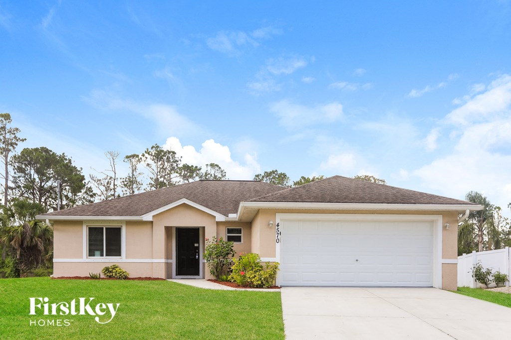 A house with a garage door and a driveway in front of it.