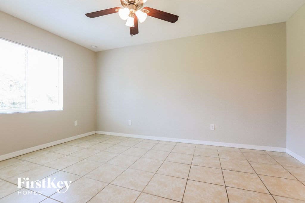 A room with a ceiling fan and tile flooring.