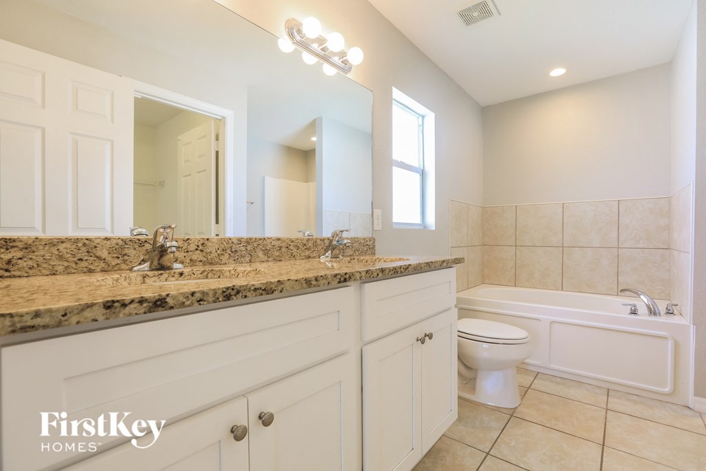 A bathroom with a marble countertop and white fixtures.