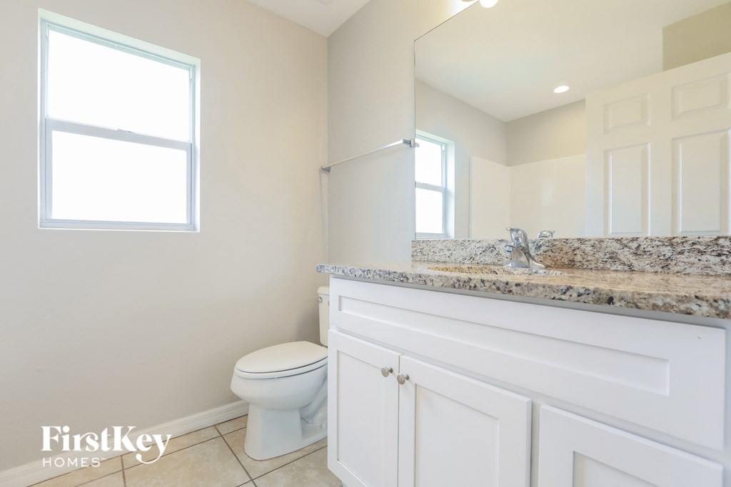 A bathroom with a toilet, sink, and mirror.