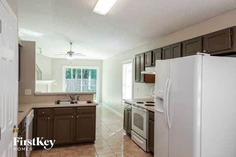A kitchen with a white refrigerator and brown cabinets.