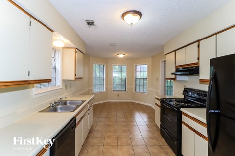 A kitchen with a black refrigerator and white cabinets.