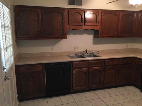 A kitchen with brown cabinets and a black dishwasher.