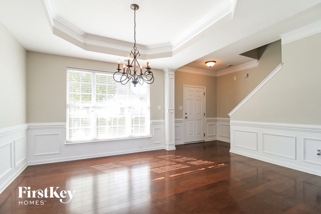 an empty dining room with a large window and a chandelier